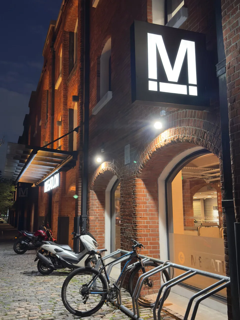 Fachada de ladrillo de los docks con un cartel iluminado y bicicletas estacionadas