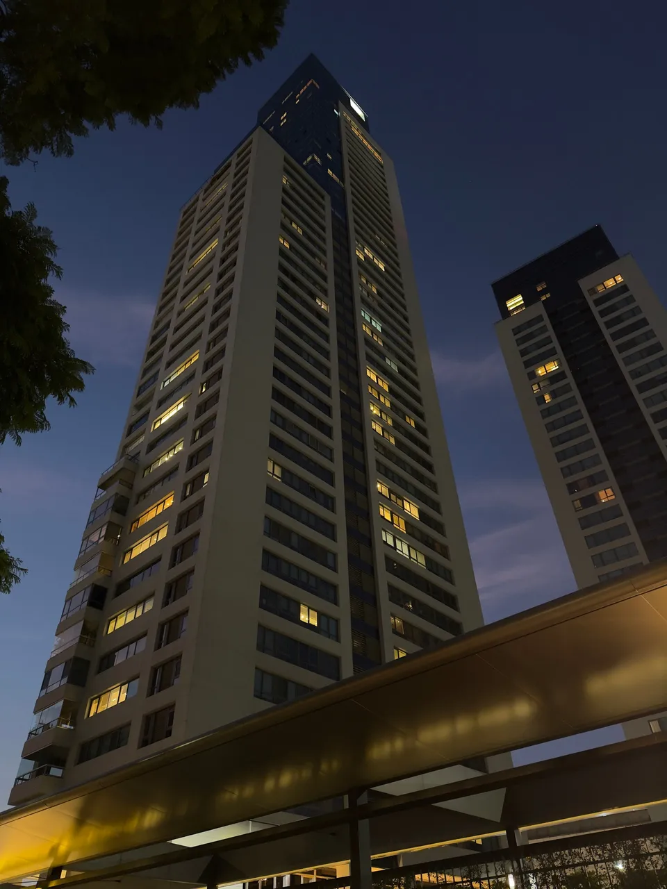 Torre de departamentos con las ventanas encendidas contra el cielo azul del anochecer