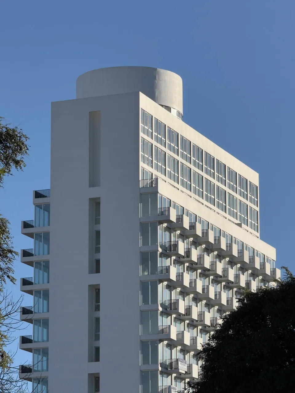 Torre blanca con tanque cilíndrico en la terraza recortada contra el cielo despejado