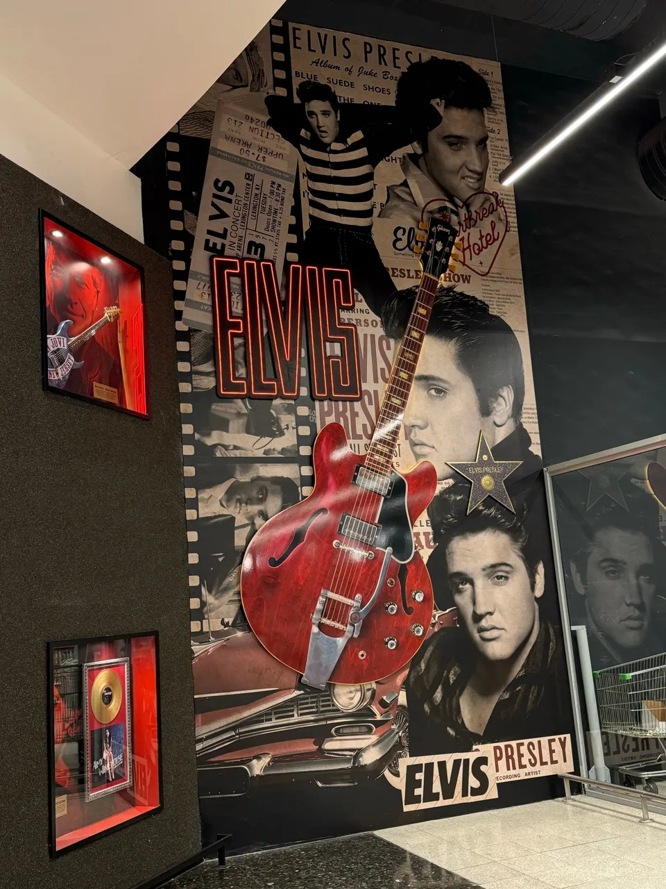 Pared con un mural de Elvis Presley y una guitarra roja colgada en el centro
